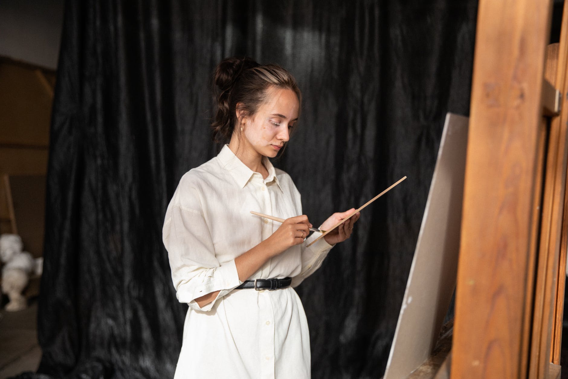 woman in white button up shirt holding a paintbrush and palette